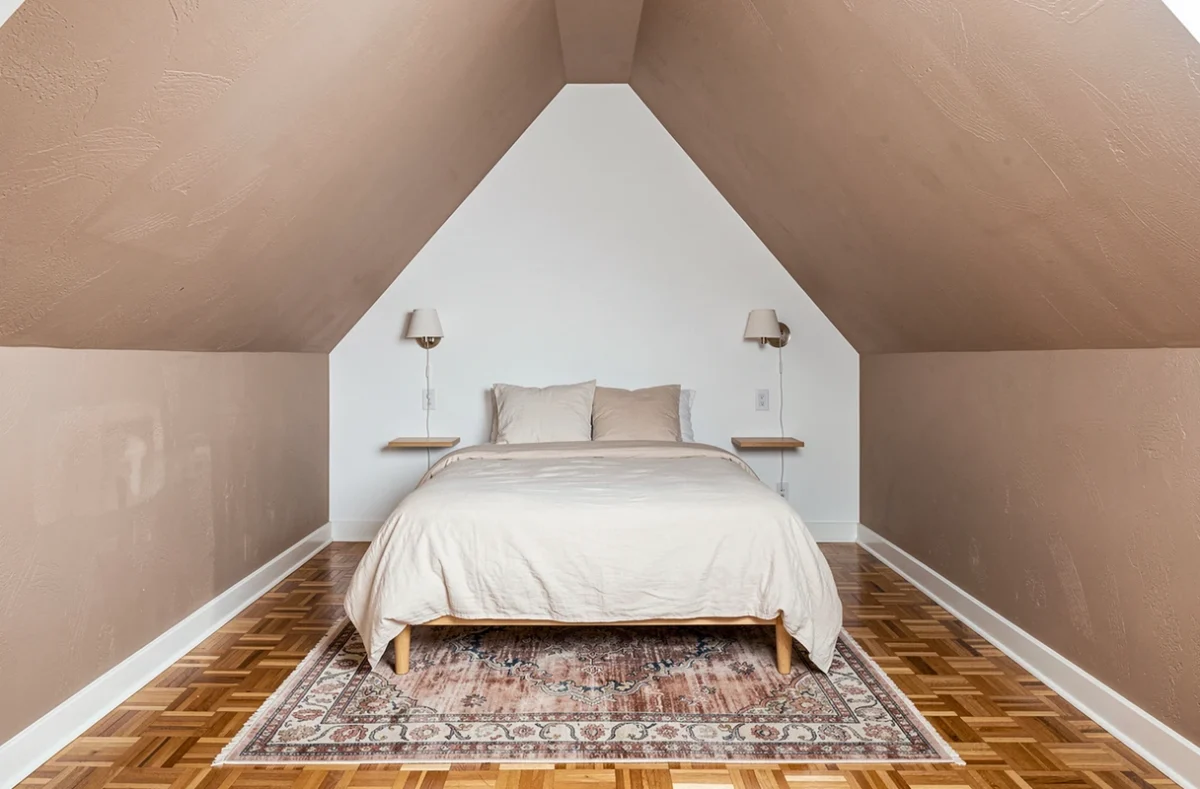 Chambre mansardée symétrique avec mur du fond blanc et plafond taupe pour agrandir visuellement la pièce en longueur