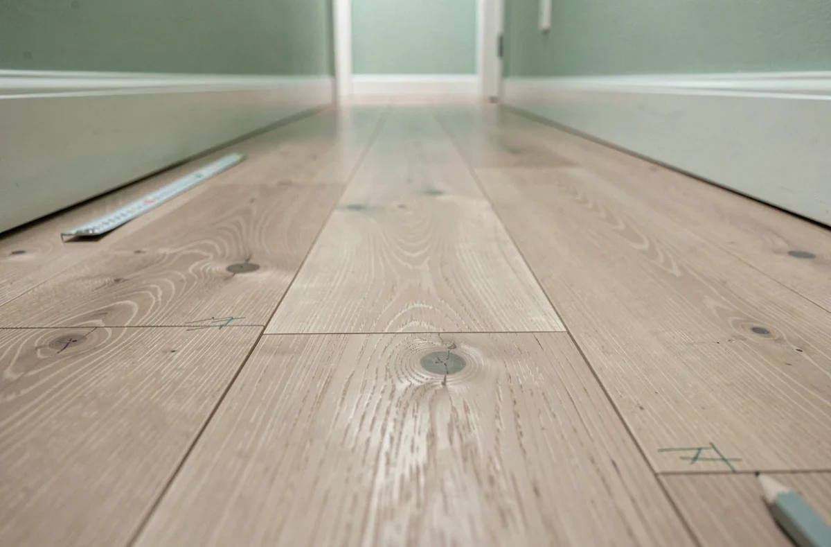 Détail de lames de parquet en frêne posées dans le sens de la longueur d'un couloir étroit